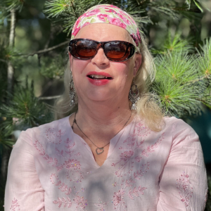Karen Renee Krebs wearing sunglasses standing in front of pine tree branches
